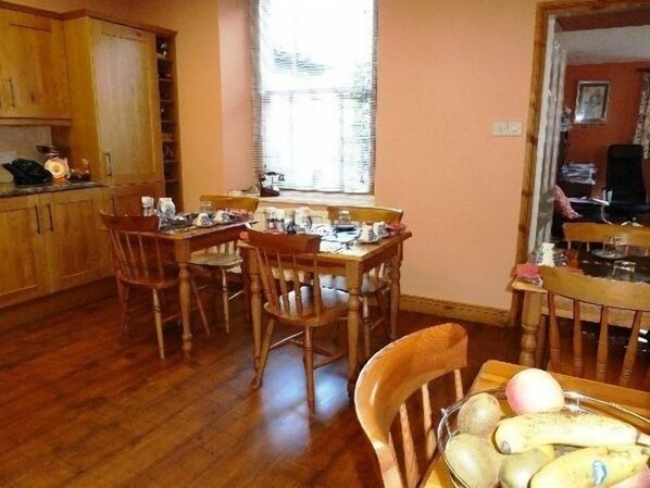 A dining area with wooden furniture and a table set for four. - College House (Windermere)