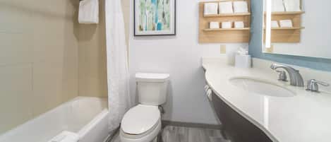 A modern bathroom with a bathtub, toilet, and vanity with a sink.