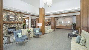 A spacious lobby with a fireplace, seating areas, and a reception desk. - Hilton Garden Inn Clifton Park (Clifton Park)
