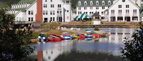 A lakeside hotel with multiple boats docked, a dock area, and a building with a green roof.