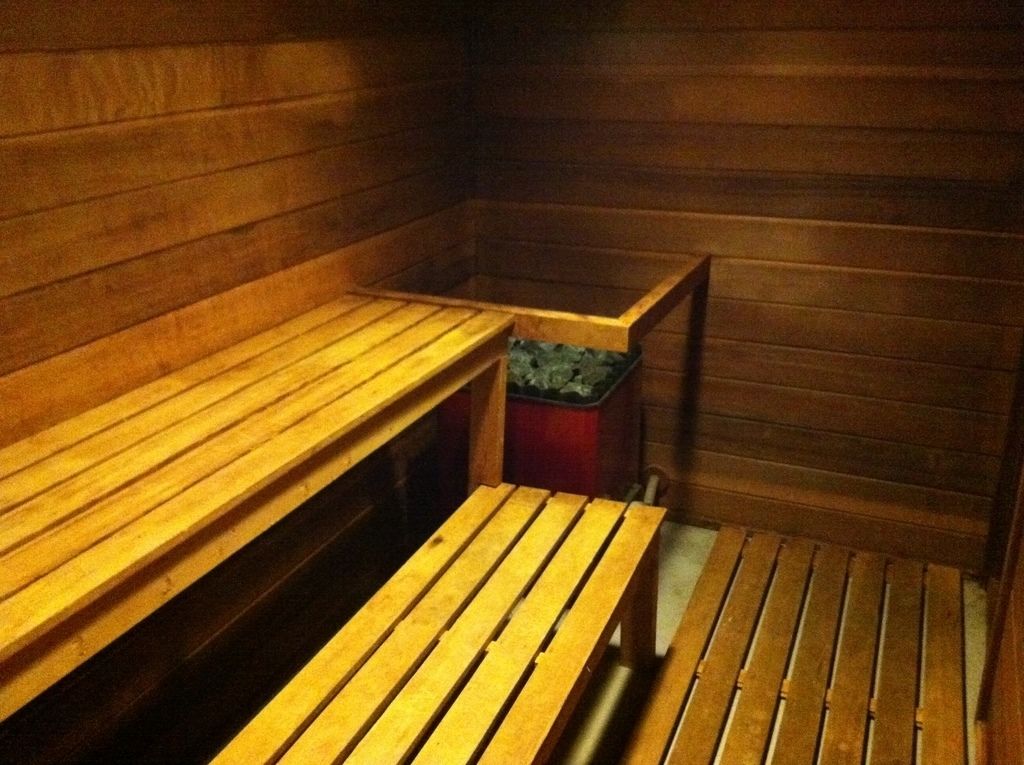 Un sauna avec des bancs en bois et une poubelle.