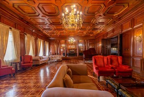 Relax in a classic room with a grand piano, ornate chandelier, and comfortable seating areas.