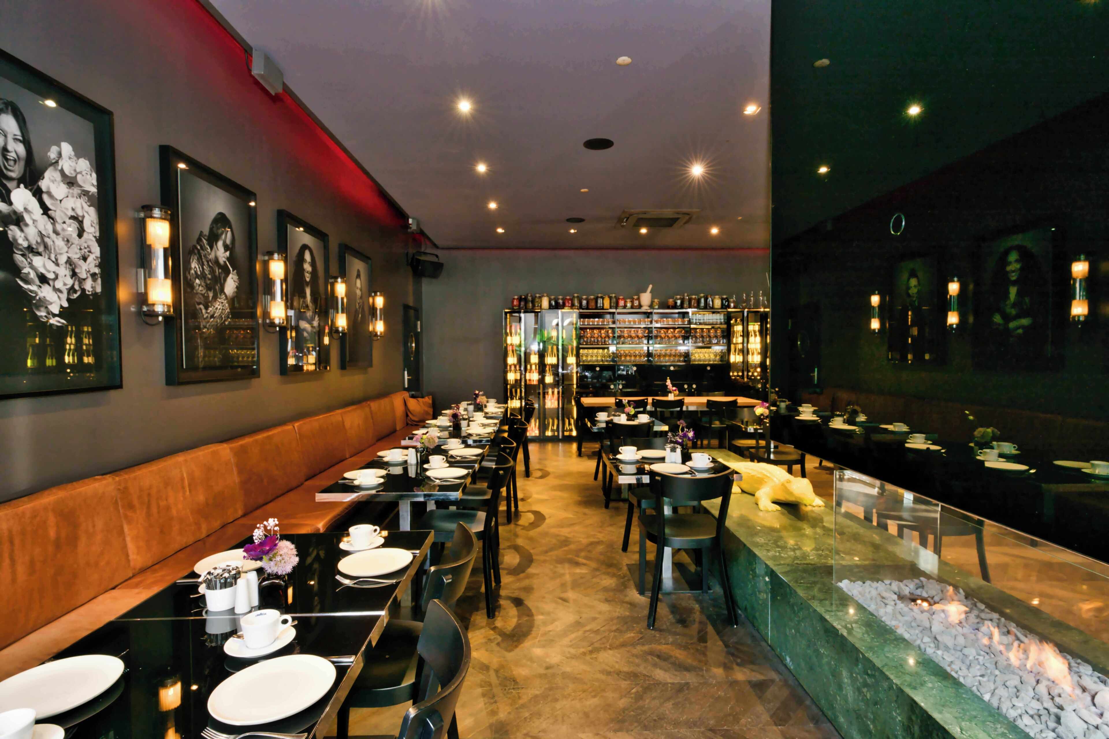 A restaurant with a long counter, multiple tables, and a bar area.