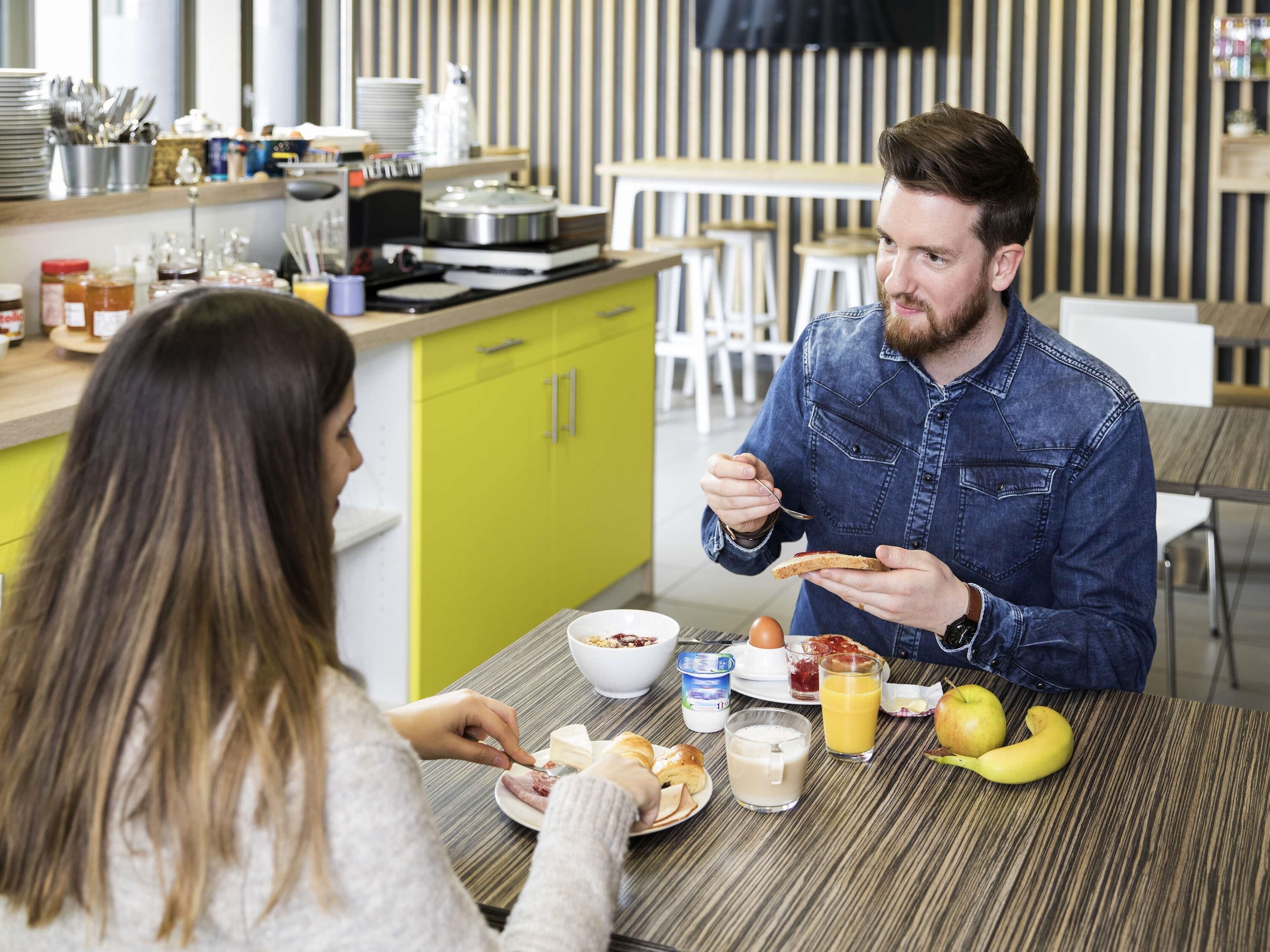 A breakfast scene with a dining table, a person eating, and various breakfast items.