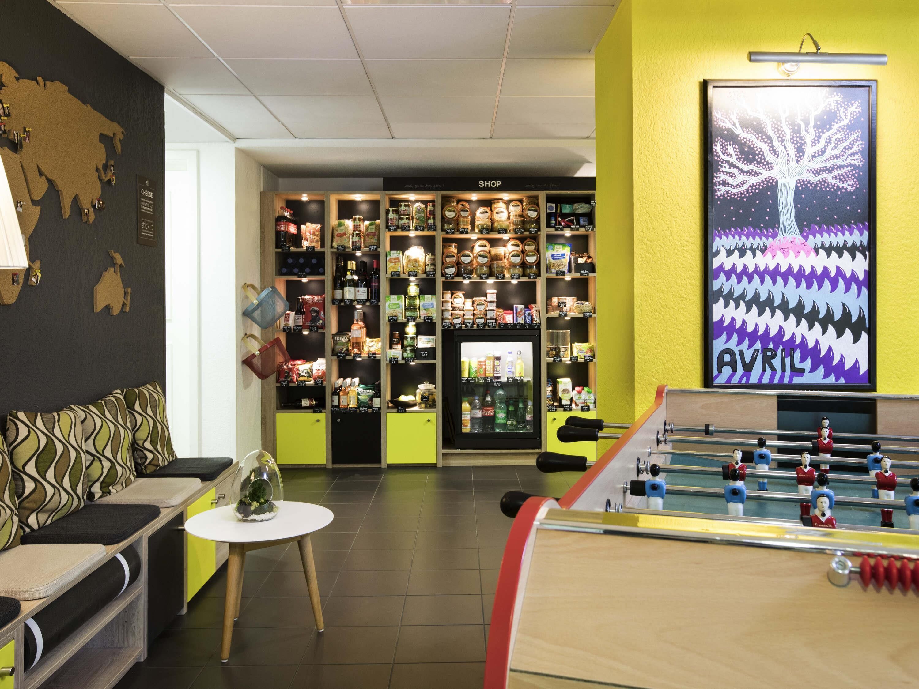 A room with a sofa, a small table, a foosball table, a wall with a map, and shelves with various items.