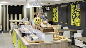 A buffet area with a variety of food items, a seating area with tables and chairs, and decorative wall art.