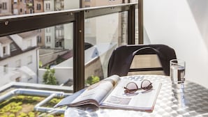 A balcony with a table, a magazine, a pair of glasses, and a glass of water.