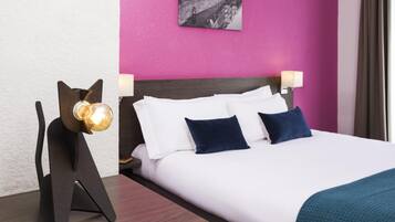 A hotel room with a bed, a nightstand with a lamp, and a wall-mounted picture.