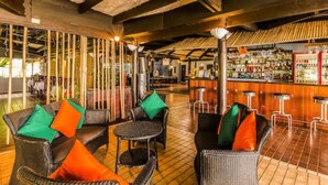 Una zona de bar con mobiliario de mimbre y suelo de baldosas.