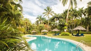 Una piscina rodeada de palmeras y sillas de descanso.