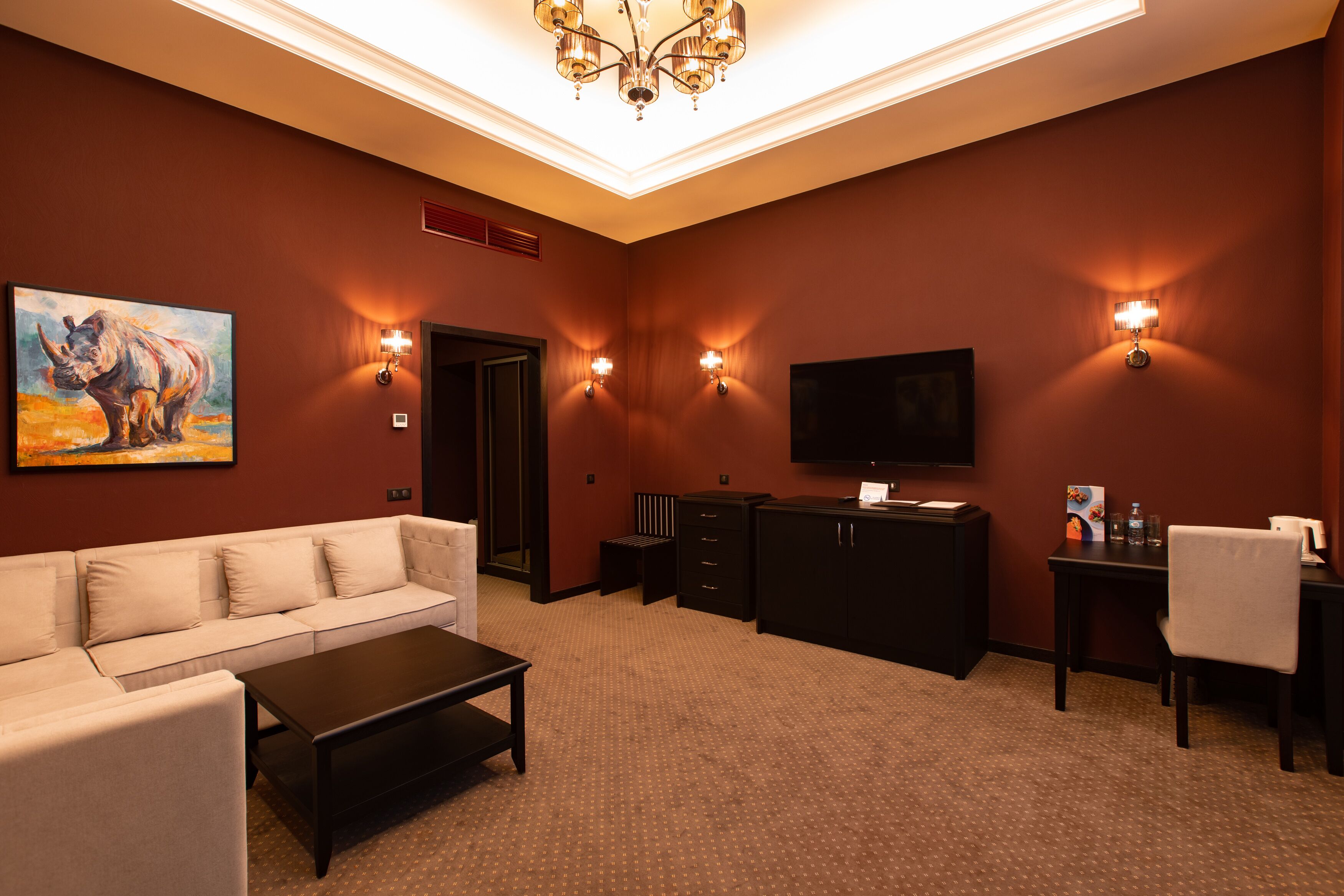 Ein modernes Wohnzimmer mit einem beige gefärbten Sofa, einem Couchtisch, einem Fernseher und einem Kamin.