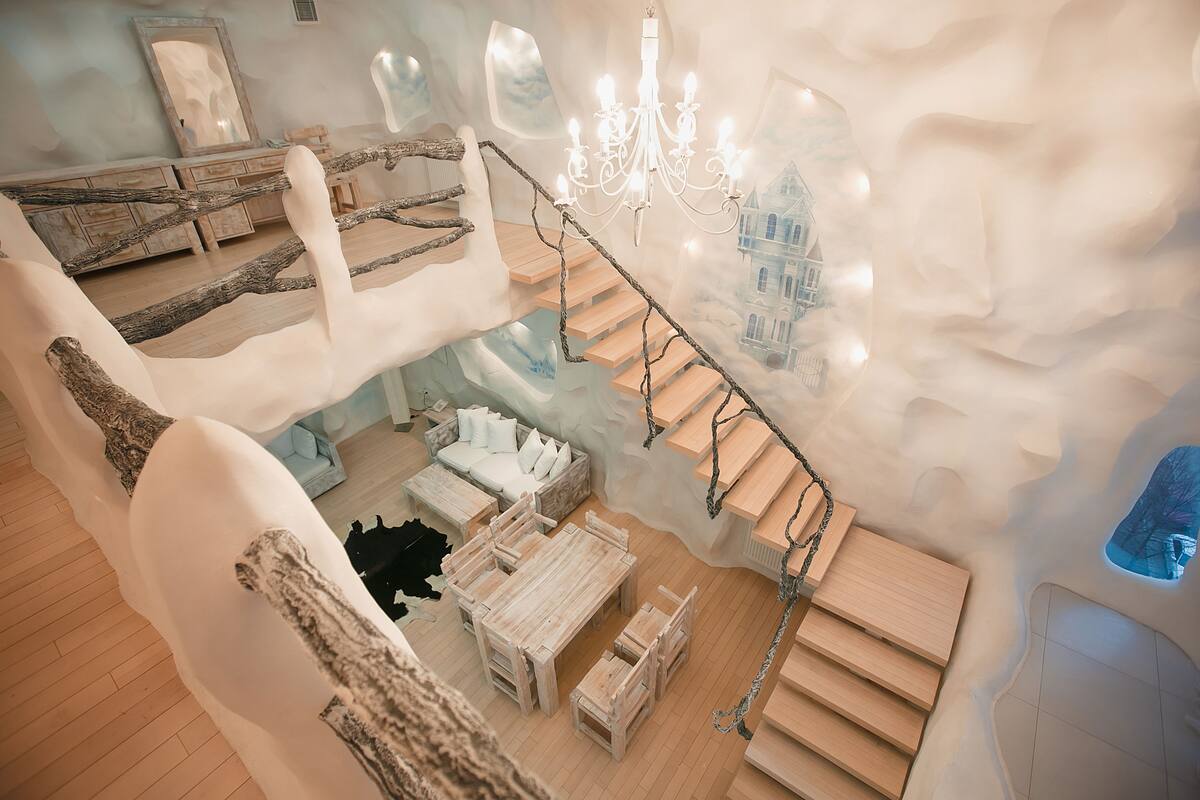 A multi-level interior with a wooden staircase, a chandelier, and a cozy seating area.