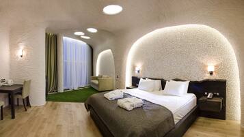 A modern hotel room with a large bed, a desk, and a seating area.