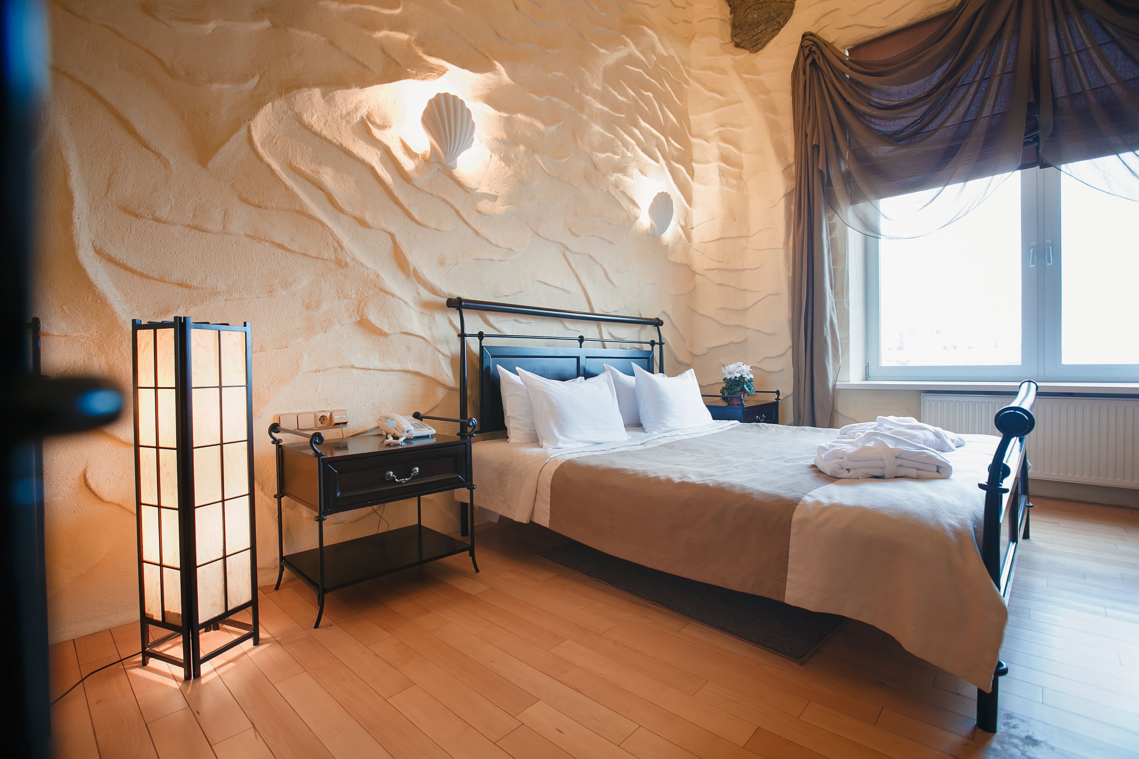 A bedroom with a bed, nightstands, a lamp, and a window with curtains.