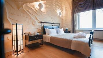 A bedroom with a bed, nightstands, a lamp, and a window with curtains.