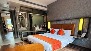 Quarto de hotel moderno com uma cama grande, uma mesa de madeira e um espaço de estar.