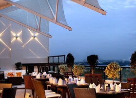 An outdoor dining area with tables set for a meal, surrounded by wicker chairs and cushioned seating.