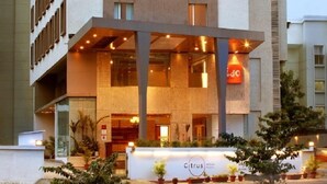 Um hotel moderno com uma área de recepção destacada, grandes janelas e uma placa com a inscrição 'Citrus Hotels'.