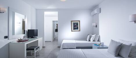 A modern hotel room with a white color scheme, a flat-screen TV, a desk with a chair, two beds, and a framed picture on the wall.