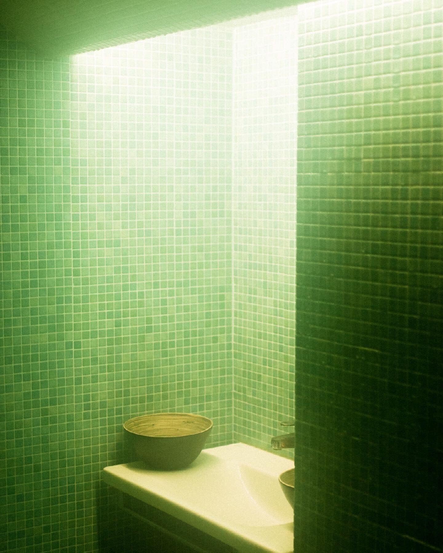 A bathroom with green tiled walls and a white sink.