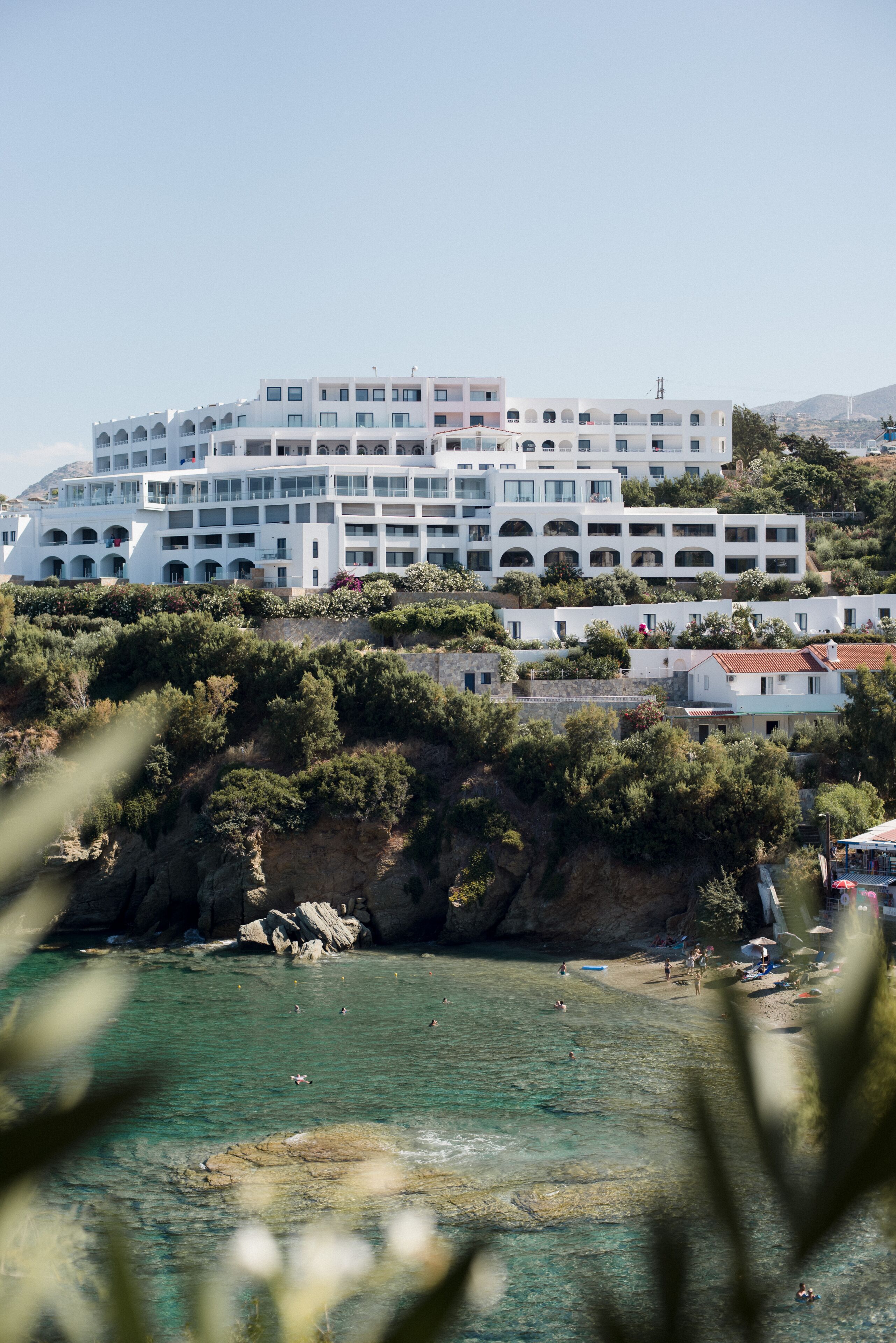 Et kysthotel med flere balkoner, en klippefyldt kystlinje og klart turkis vand.