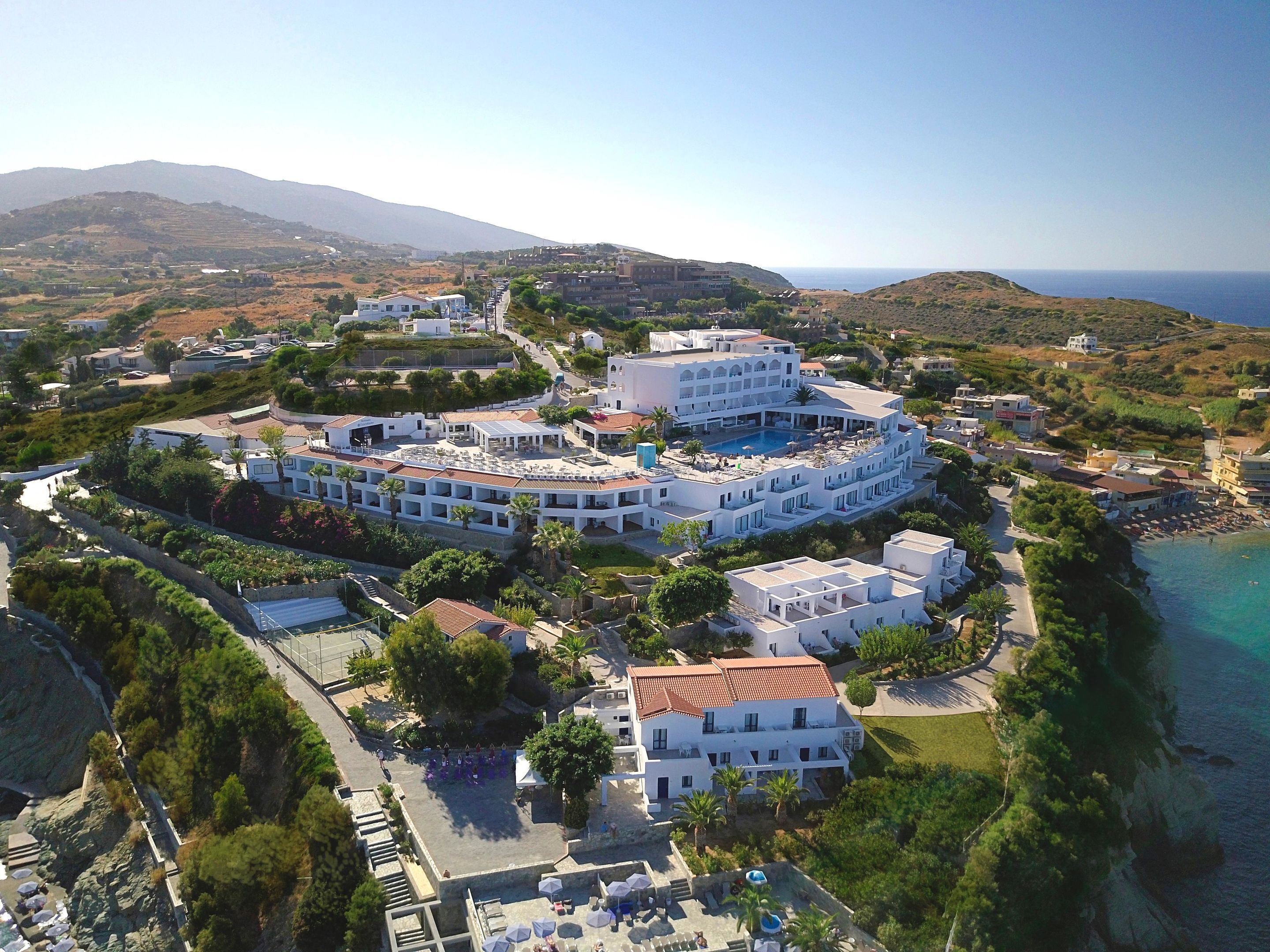 A coastal hotel with multiple buildings, a swimming pool, and a beach view.