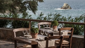 A table set for dining with a view of the sea and a rocky outcrop. - Peninsula Resort & Spa - All Inclusive (Malevizi)