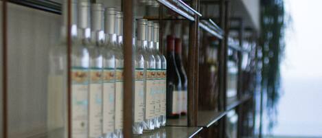 A bar area with shelves of bottles and glasses, wooden crates, and a view of the outdoors.