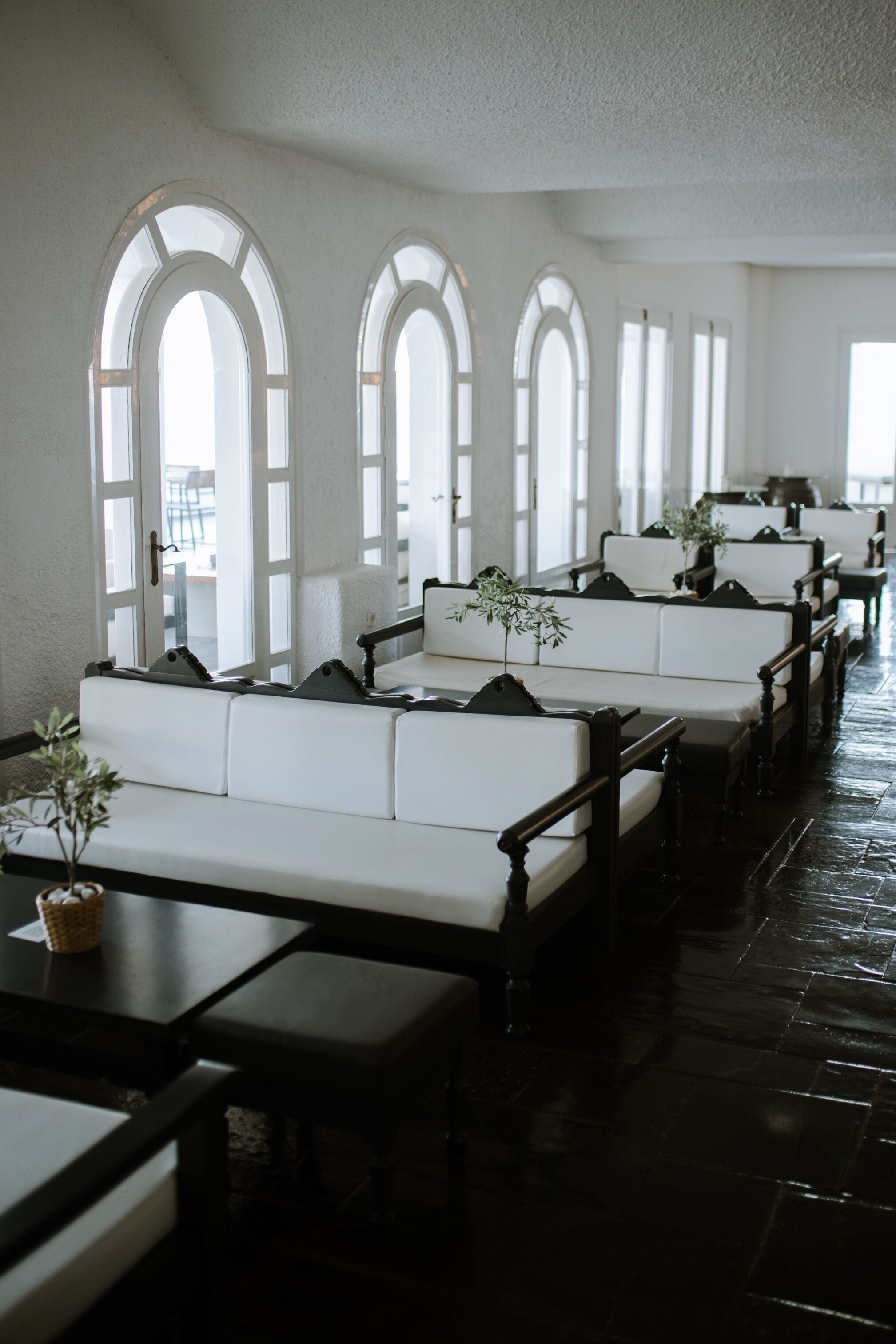 A row of white cushioned benches with black armrests, arranged in a linear fashion along a polished black floor.