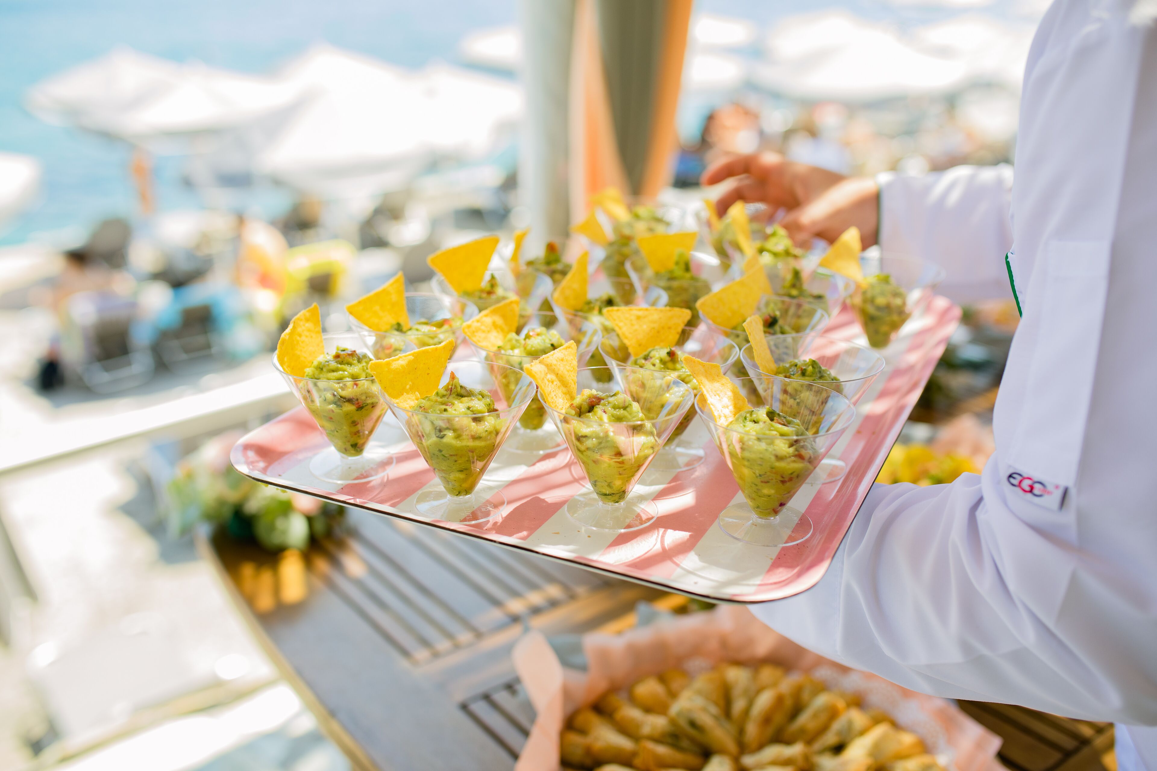 A tray of appetizers with a person in a white coat holding it.