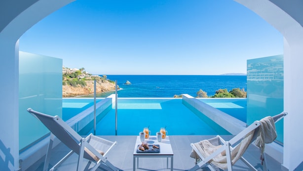 A balcony with a clear view of the sea, a pool, and two lounge chairs. - Peninsula Resort & Spa - All Inclusive (Malevizi)