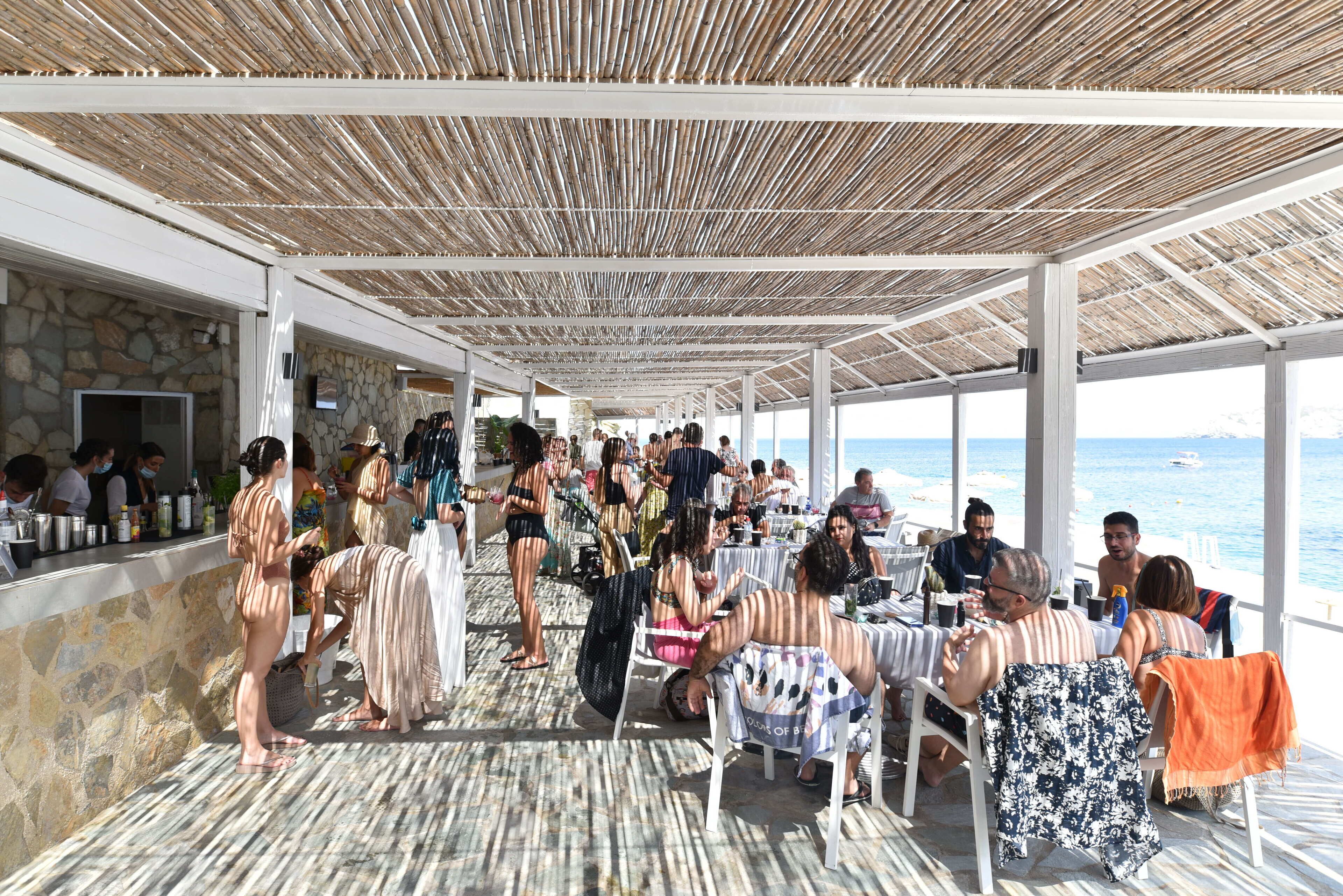 A covered outdoor dining area with stone walls and a view of the sea.