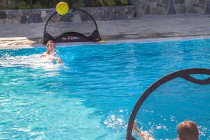 Una piscina con agua azul cristalina, una estructura negra flotante y una persona nadando.