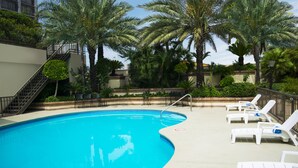 A swimming pool with lounge chairs and palm trees. - iStay Hotel Monterrey Histórico (Monterrey)