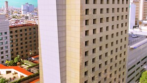 A tall hotel with a prominent iStay logo, multiple floors, and a rooftop area with palm trees. - iStay Hotel Monterrey Histórico (Monterrey)
