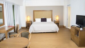 A hotel room with a large bed, bedside tables with lamps, a TV on a wooden cabinet, a desk with a chair, and a window with curtains. - iStay Hotel Monterrey Histórico (Monterrey)