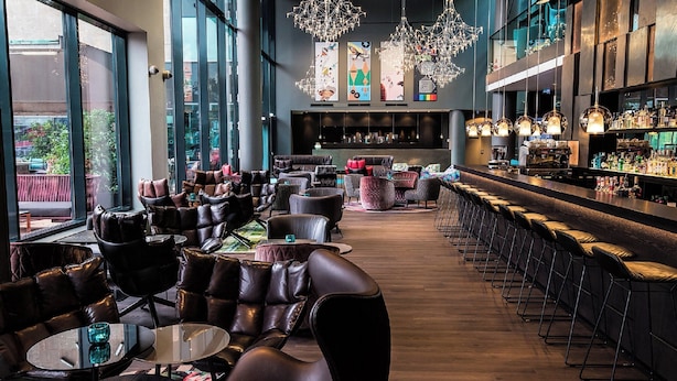 A modern bar area with leather seating, a long counter, and decorative lighting. - Motel One Wien-Westbahnhof (Vienna)