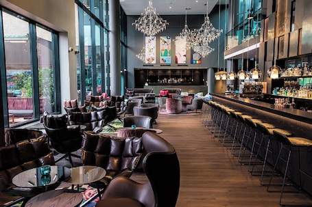 A modern bar area with leather seating, a long counter, and decorative lighting.
