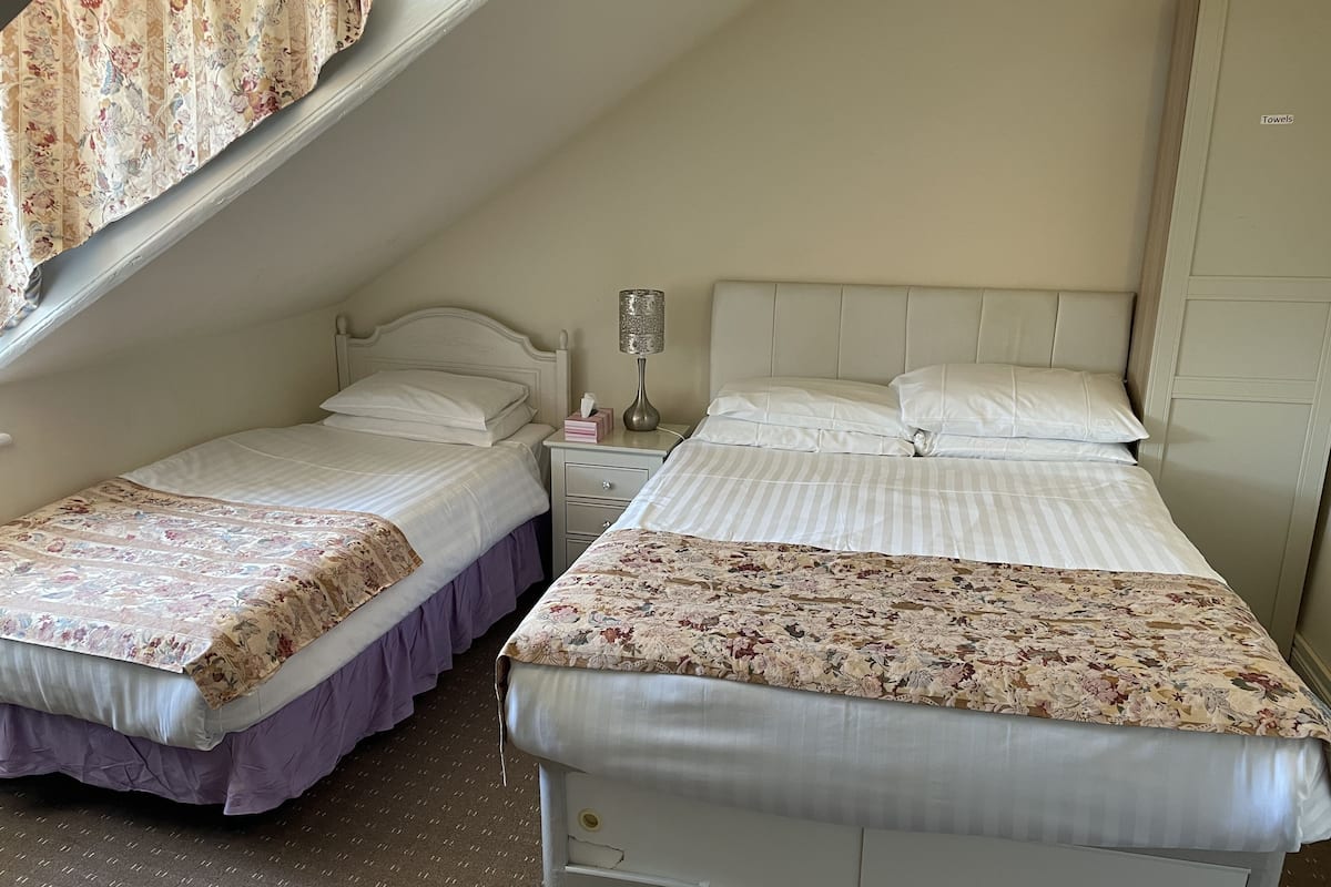 Une chambre avec deux lits, une table de chevet et une fenêtre avec des rideaux.