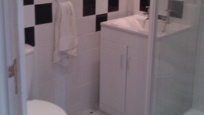Un baño pequeño con inodoro blanco, lavamanos y ducha.