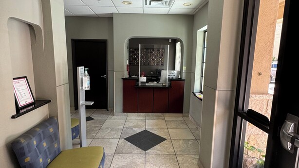 A hotel lobby with a reception desk, a waiting area with a cushioned bench, and a tiled floor. - Cityview Inn & Suites Downtown RiverCenter Area (San Antonio)