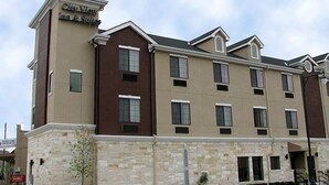 A multi-story hotel with a beige and brown facade, multiple windows, and a stone base. - Cityview Inn & Suites Downtown RiverCenter Area (San Antonio)