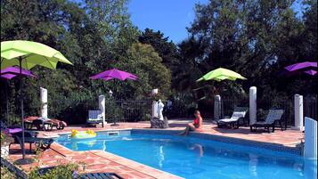 Una piscina al aire libre de temporada, sombrillas