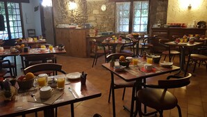 Un comedor rústico con mesas y sillas de madera, paredes de piedra y un mostrador de piedra.