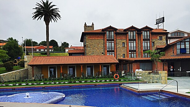 A hotel with a swimming pool, outdoor seating, and a sign indicating a hotel. - Hotel Marfrei (Suances)