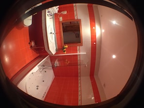 A bathroom with a bathtub, a mirror, and red and white tiled walls. - Hotel Marfrei (Suances)