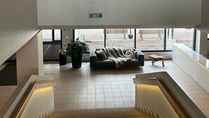 A modern interior with a staircase, a couch, and a wall with geometric wooden art. - Hotel Waltikka (Valkeakoski)