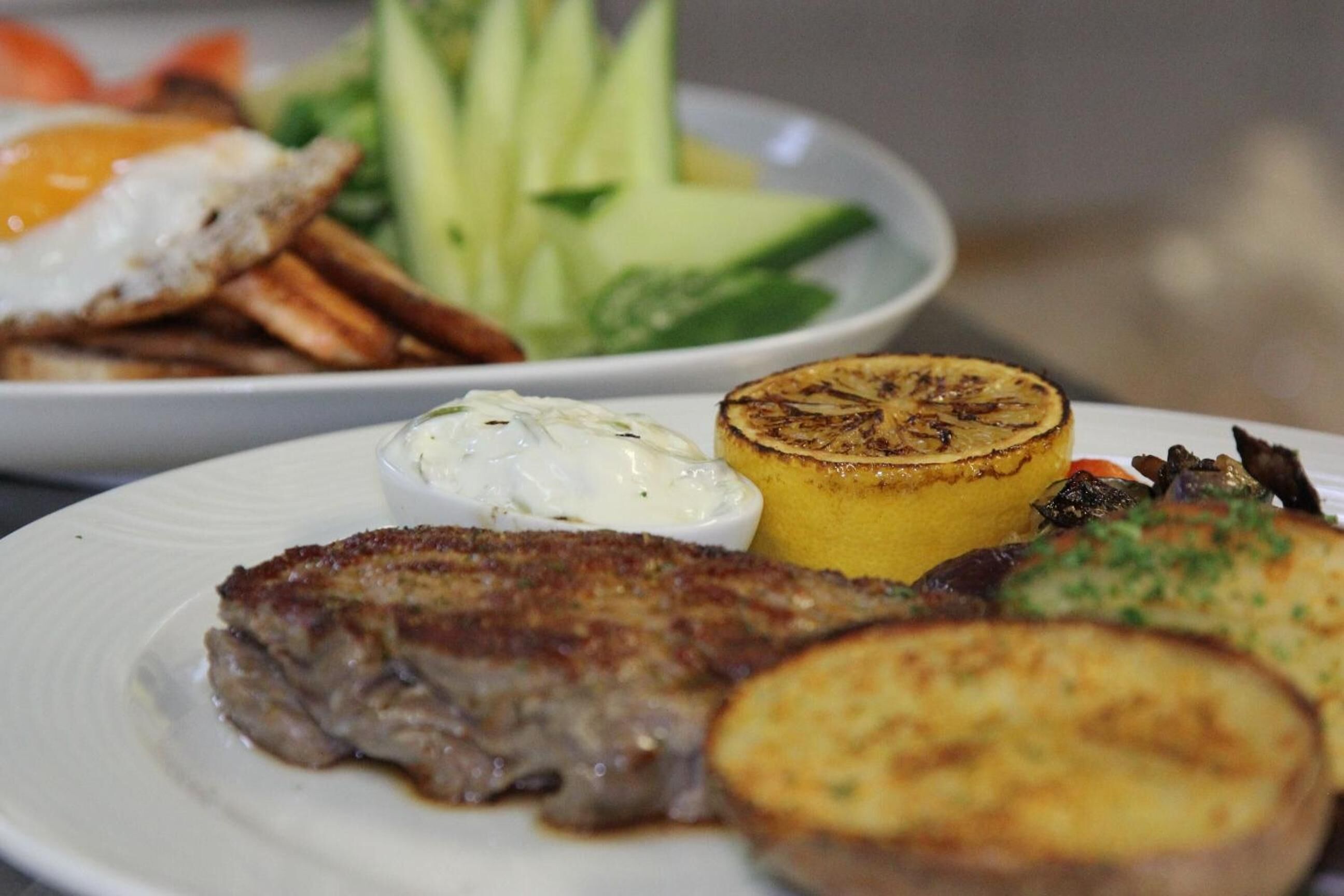 Un plato con carne a la parrilla, papas y verduras.