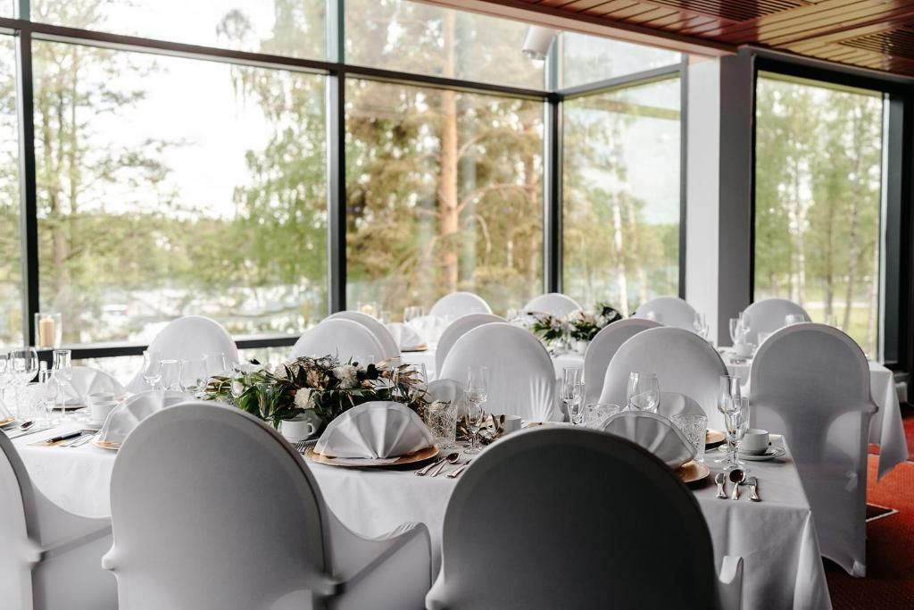 Una mesa de banquete dispuesta para un evento formal, con sillas blancas y vajilla.