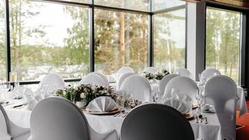 Una mesa de banquete dispuesta para un evento formal, con sillas blancas y vajilla.